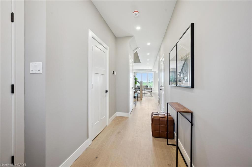 Light wood-finish flooring, recessed ceiling lighting, three-panel interior doors, and pale gray wall finishes