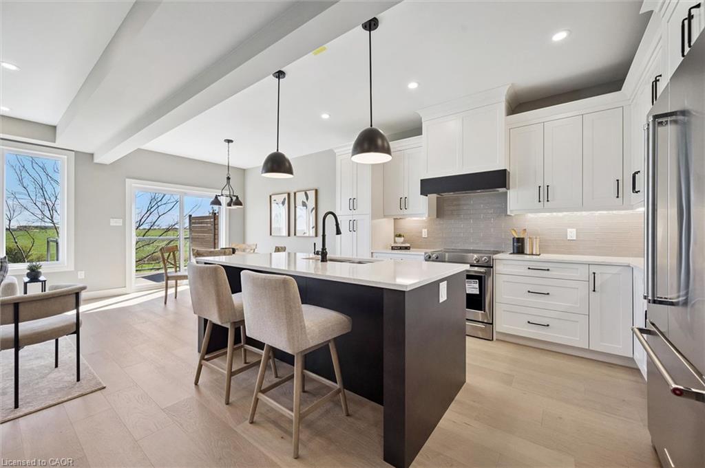Kitchen featuring a dark island with white countertop, pendant lighting, stainless steel appliances, and wood-finish flooring