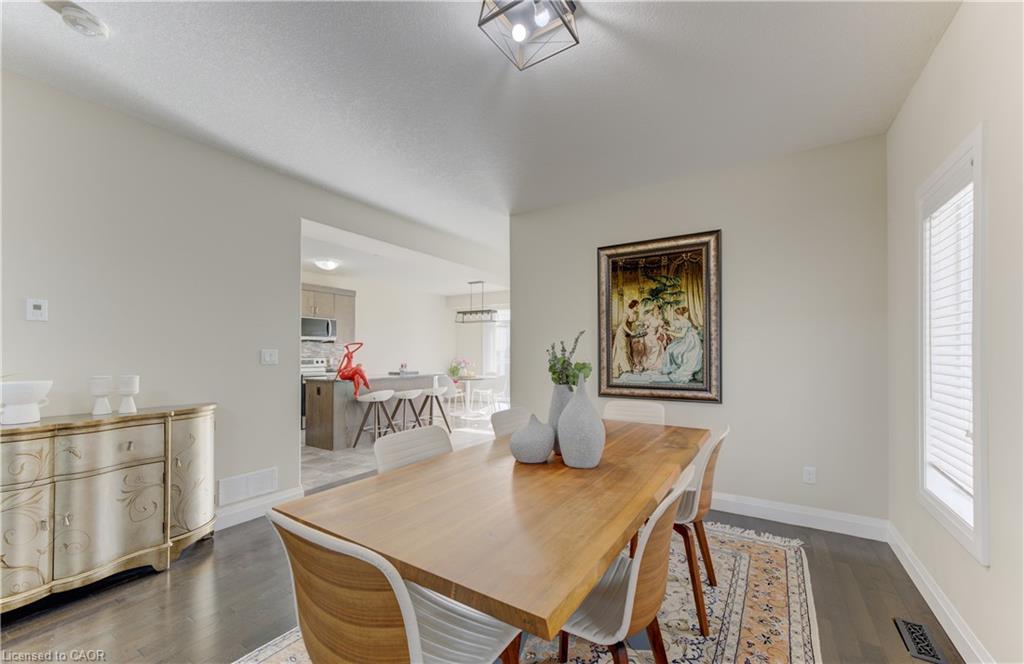 Hardwood flooring, light-toned wall paint, contemporary light fixture, large window, kitchen with stainless steel appliances