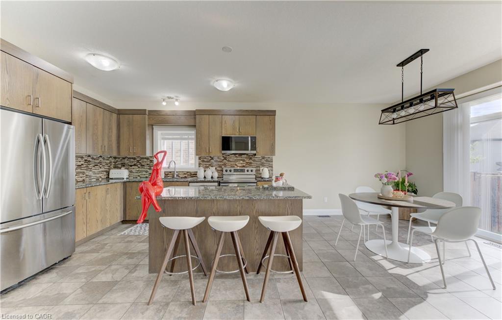Stainless steel appliance suite, granite island countertop, wood-finish cabinetry, tile flooring, and a sliding glass door