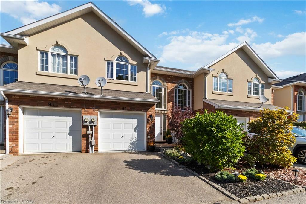 Elegant two-story residence featuring a cream-colored exterior with brick accents, arched entryways, and architectural detailing