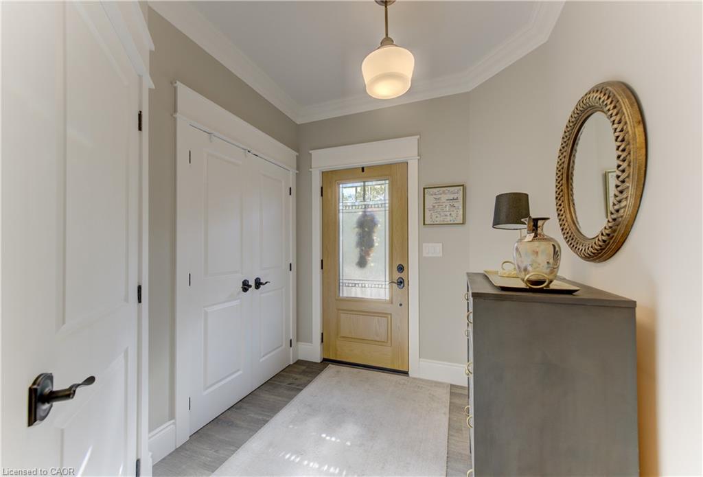 Wood-finish flooring, white paneled doors, crown molding, and a light wood-tone entry door with decorative glass