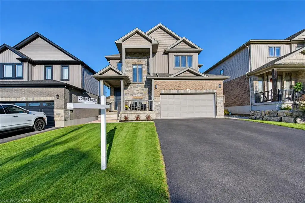 Two-story exterior featuring stone veneer accents, horizontal siding, a covered entryway, a double-car garage, and a paved driveway