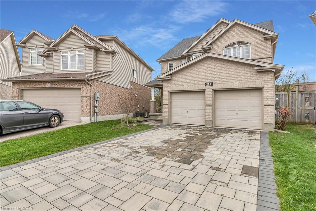 Brick and siding exterior featuring a two-car garage, arched window, and a paver stone driveway