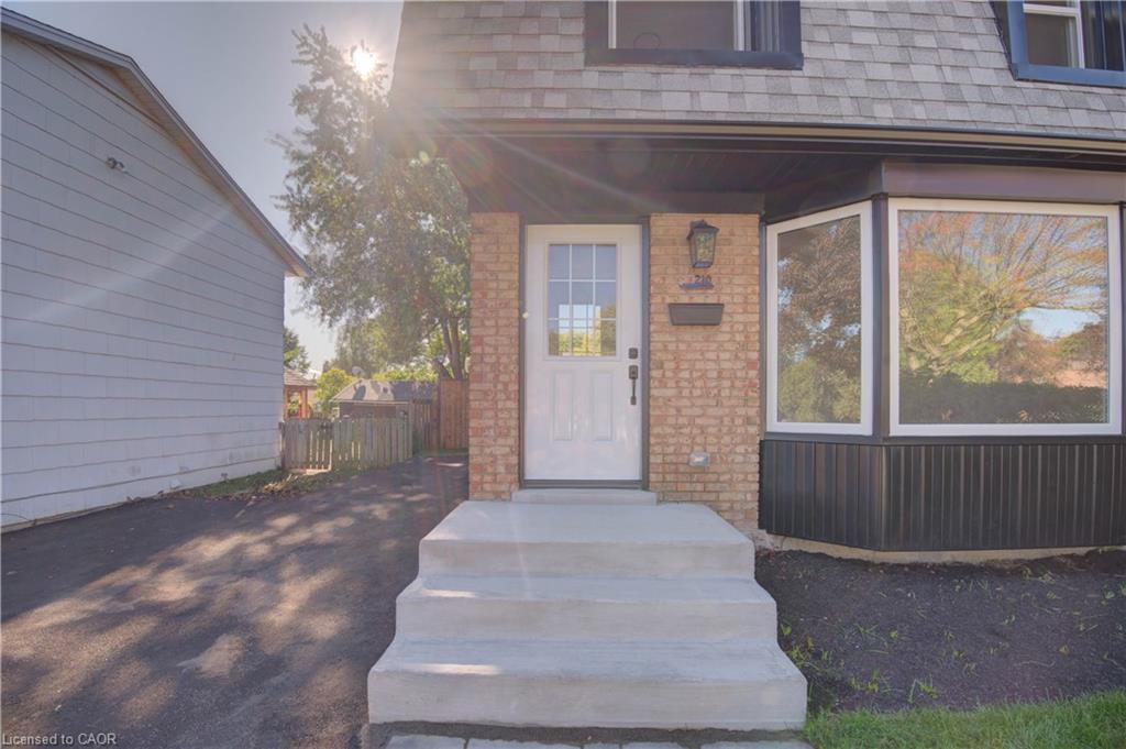 Brick exterior with a prominent bay window, asphalt driveway, concrete entry steps, and a glass-paneled entry door