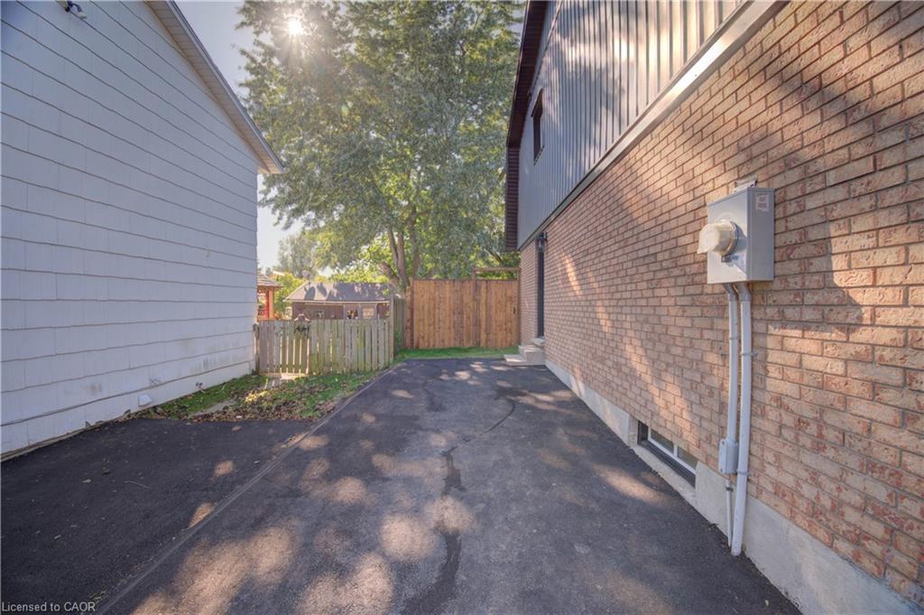 Brick exterior with a utility meter, a finished basement window, and an asphalt driveway