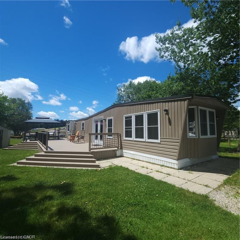 Expansive outdoor deck with multiple levels, vinyl siding exterior, multiple windows, and a gravel patio area
