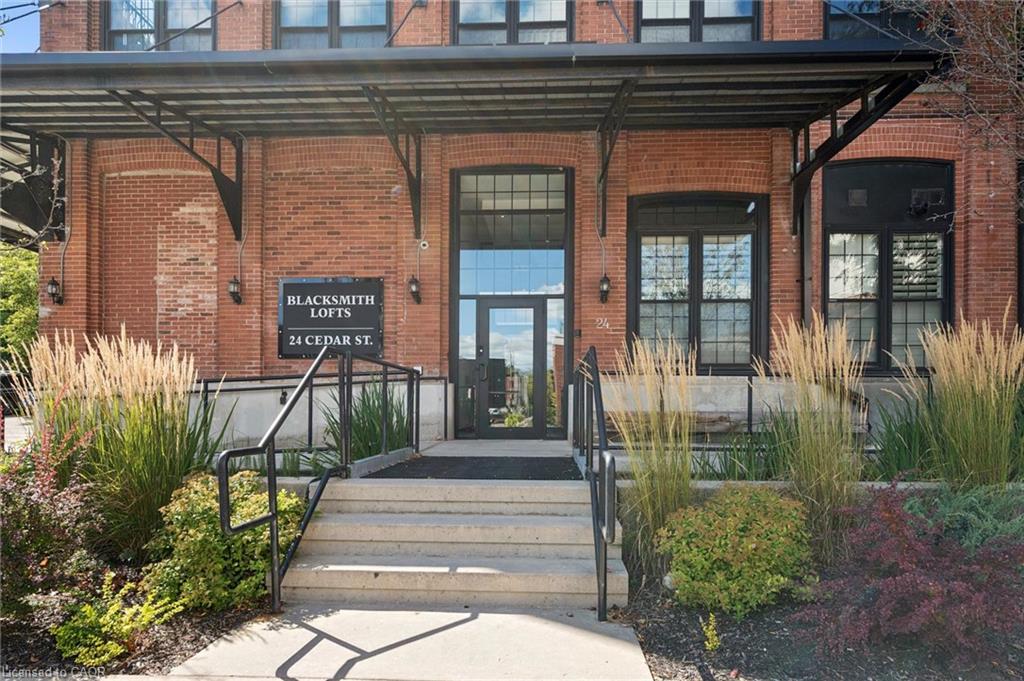 Brick facade with a metal awning, concrete steps, and black handrails