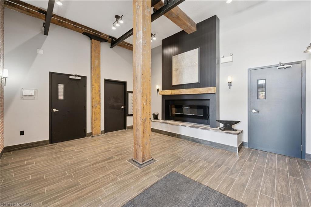 Exposed wood beams, wood-finish tile flooring, recessed lighting, and a modern fireplace with a stone hearth
