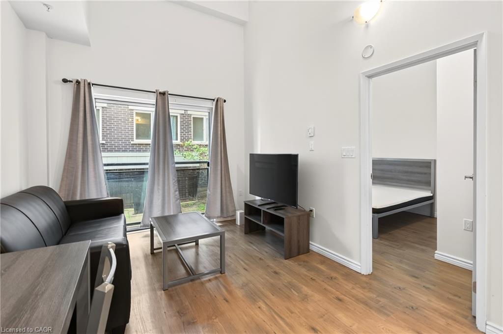 Wood-finish flooring throughout, bright white walls, and a glass-paneled door leading to an outdoor space