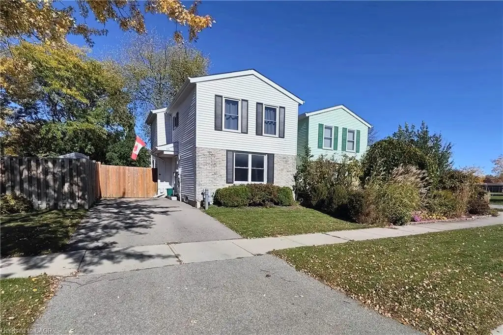 Two-story exterior featuring white vinyl siding, a masonry lower facade, dark shutters, and an asphalt driveway