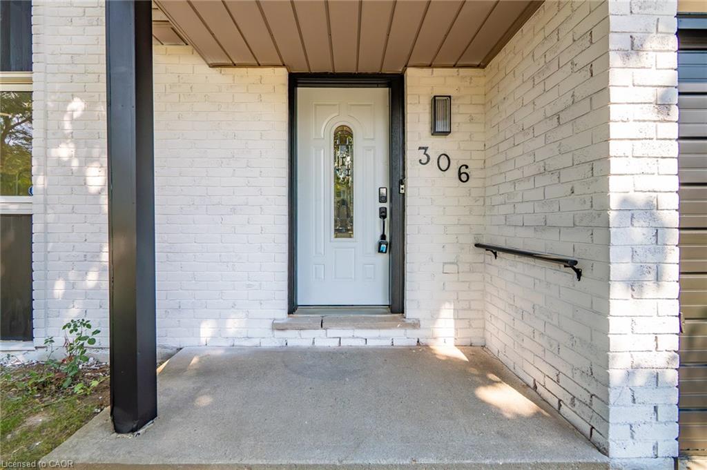 White brick facade with a concrete front porch, white entry door with an arched glass insert, and a black exterior light fixture