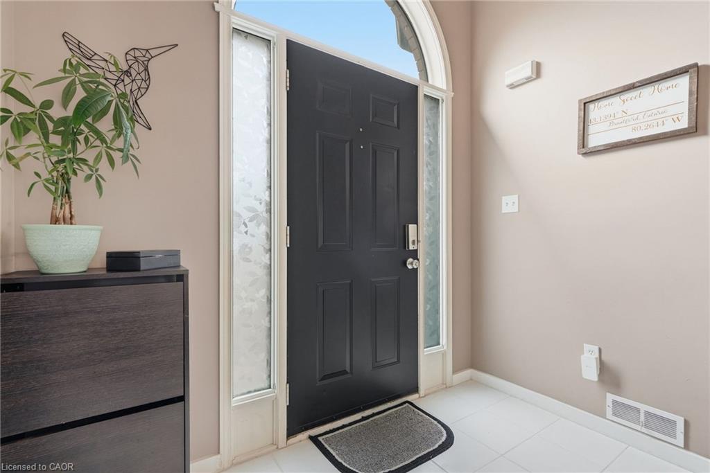 Arched transom entry with a paneled door, decorative frosted glass sidelights, and white tile flooring