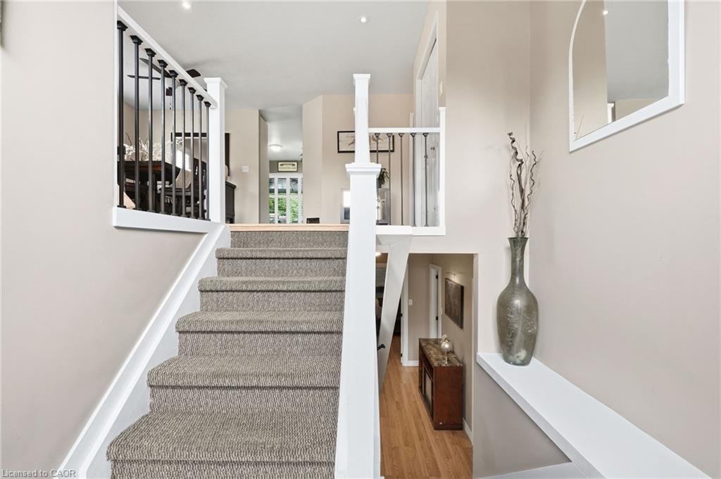 Carpeted staircase with white risers, black metal balusters, and wood-finish flooring