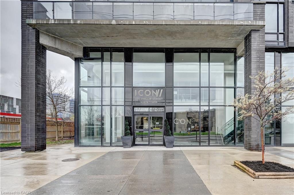 Contemporary building entrance featuring a prominent concrete canopy, dark brick columns, and a glass facade