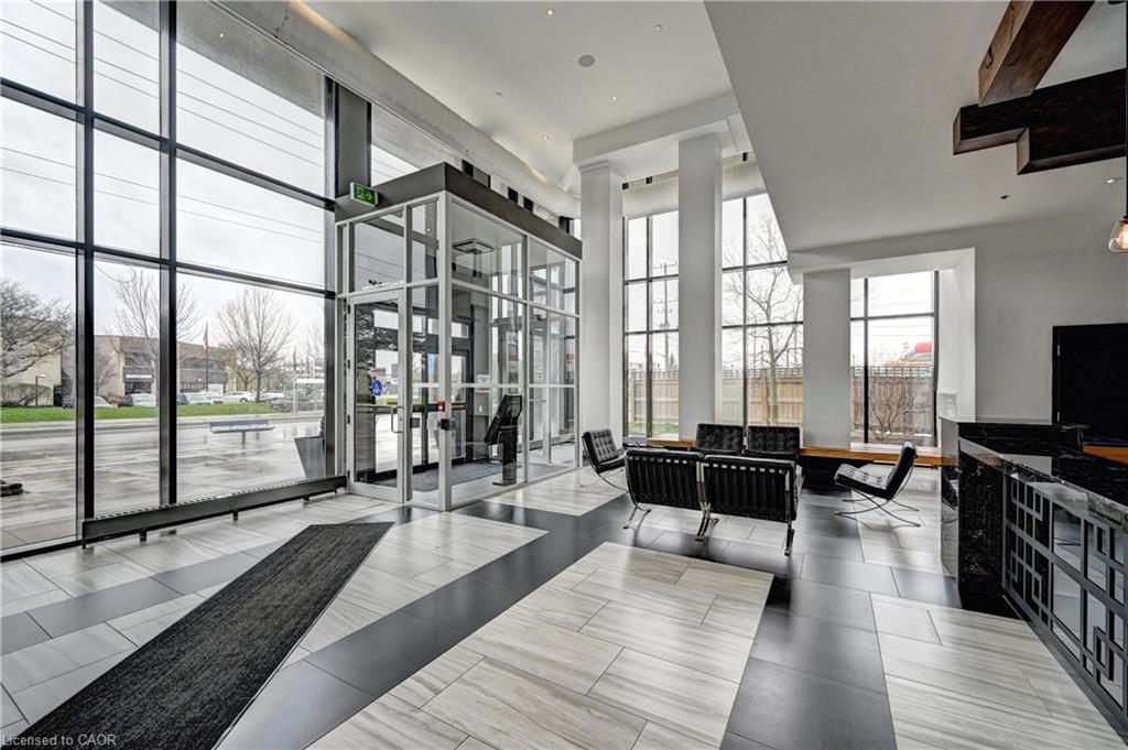 Spacious entryway featuring a full-height glass wall, high ceilings, a built-in reception desk with a dark countertop, and a modern light-toned flooring pattern