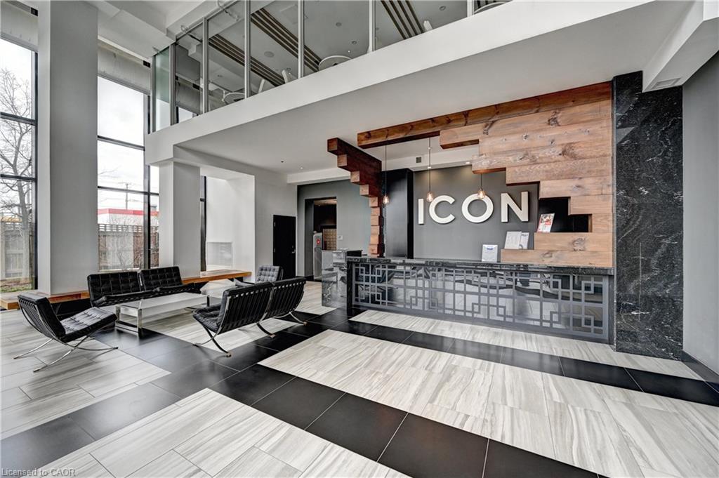 Two-story lobby featuring a wood-finish accent wall, dark stone wall paneling, and a geometric-patterned reception desk