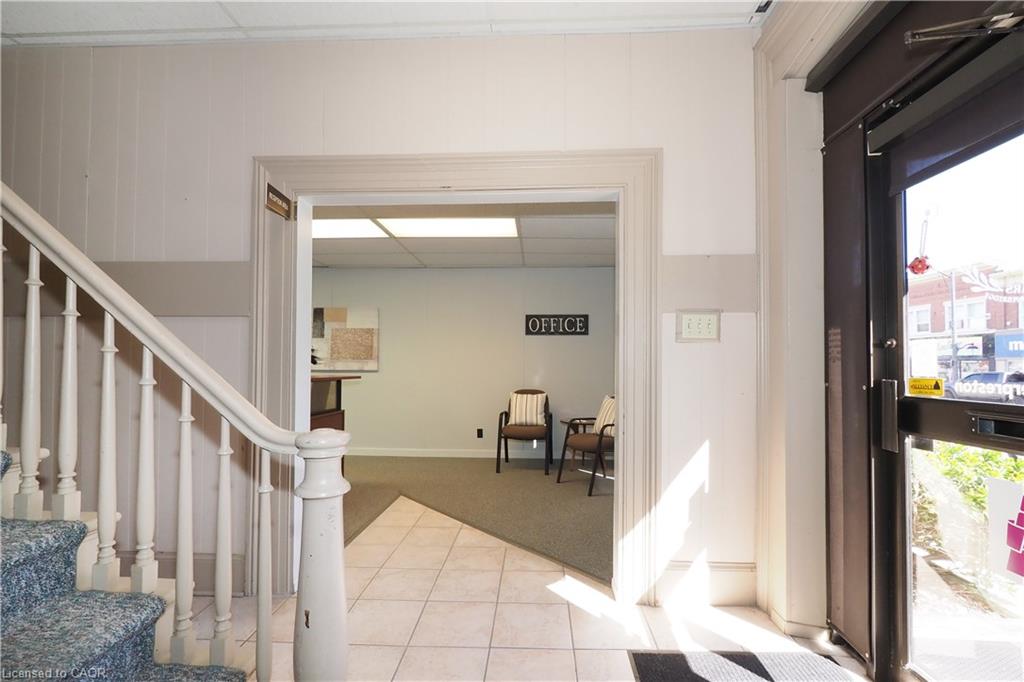 Entryway featuring a glass-paneled commercial door, white paneled walls, and ceramic tile flooring