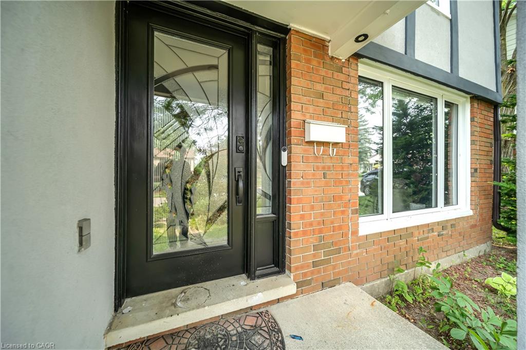 Entryway featuring a black door with decorative glass, a sidelight, and a white mailbox against a brick facade