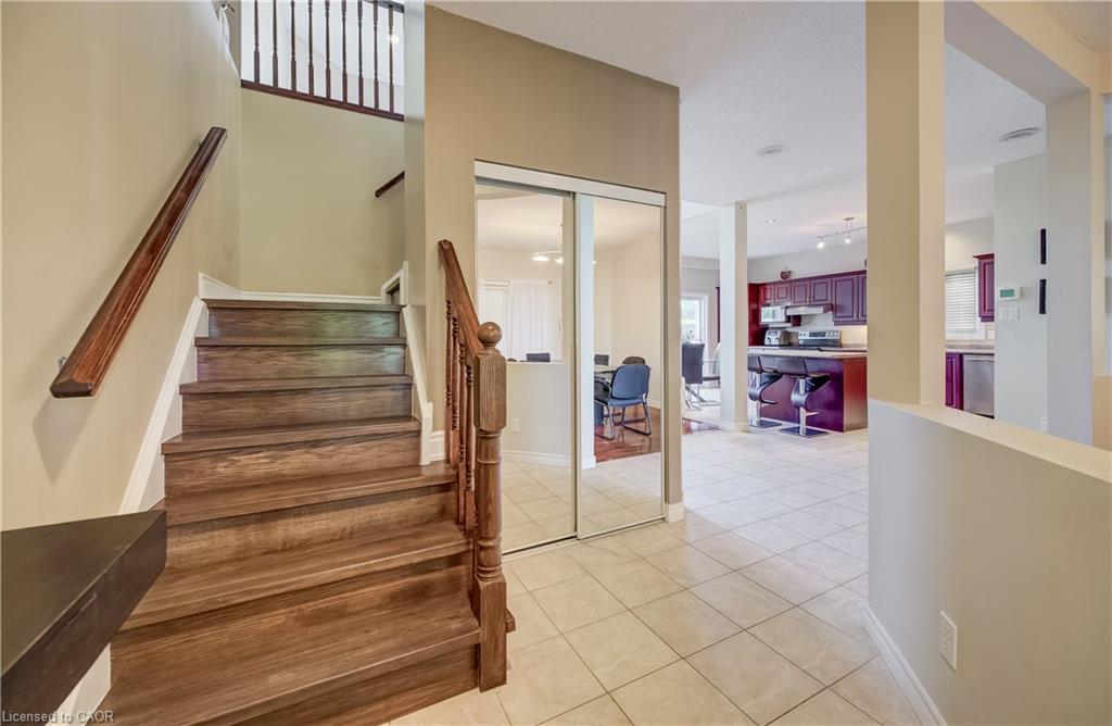Hardwood stairs with a classic wood banister, mirrored closet doors, and tile flooring