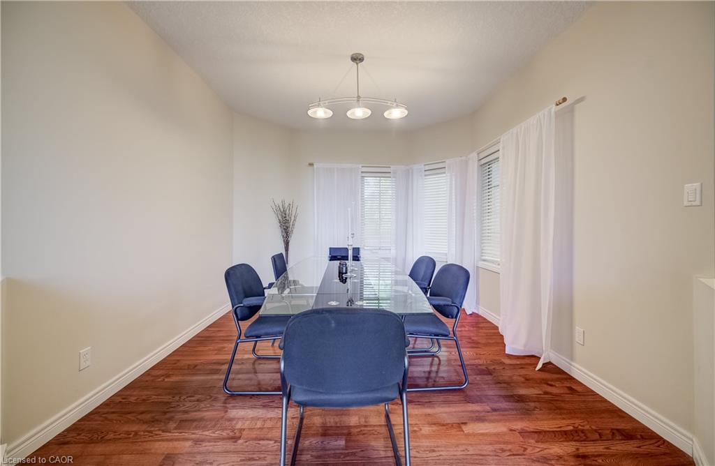 Bay window with white blinds and sheer curtains, wood-finish flooring, and a contemporary ceiling light fixture