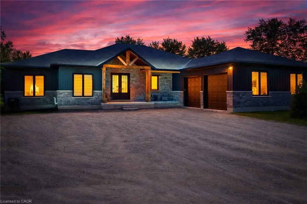 View of front of property featuring stone siding, an attached garage, covered porch, dirt driveway, and board and batten siding