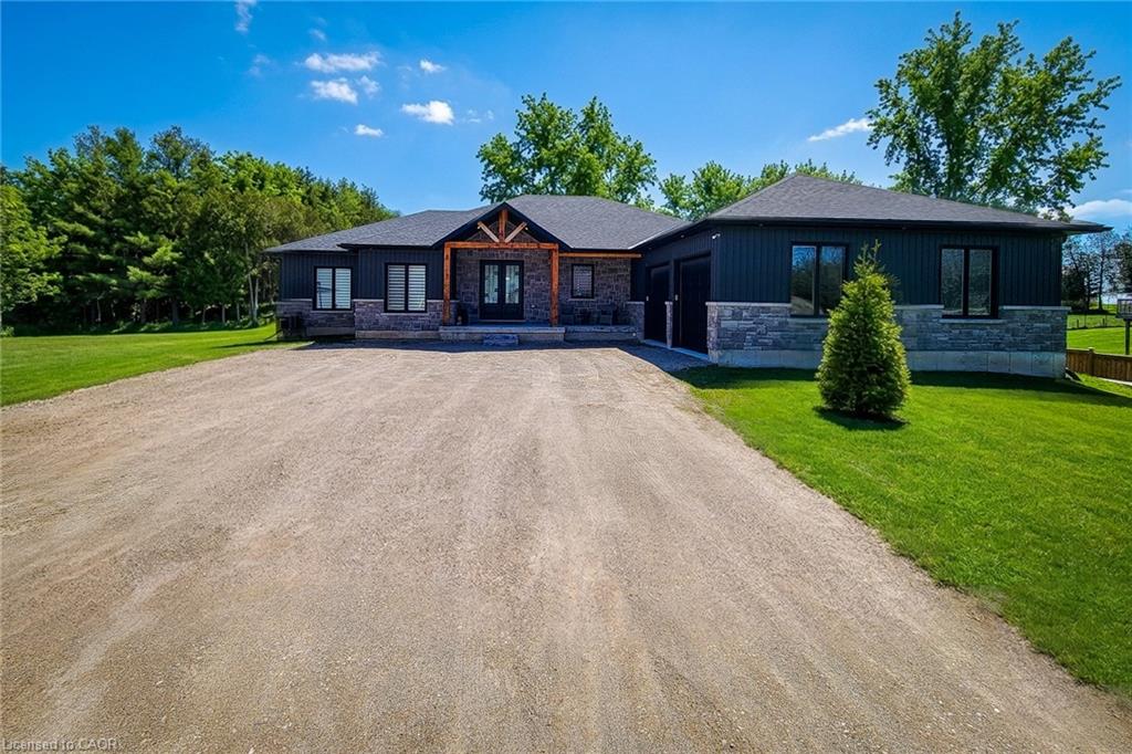 View of front of property featuring stone siding, dirt driveway, a garage, and a front yard