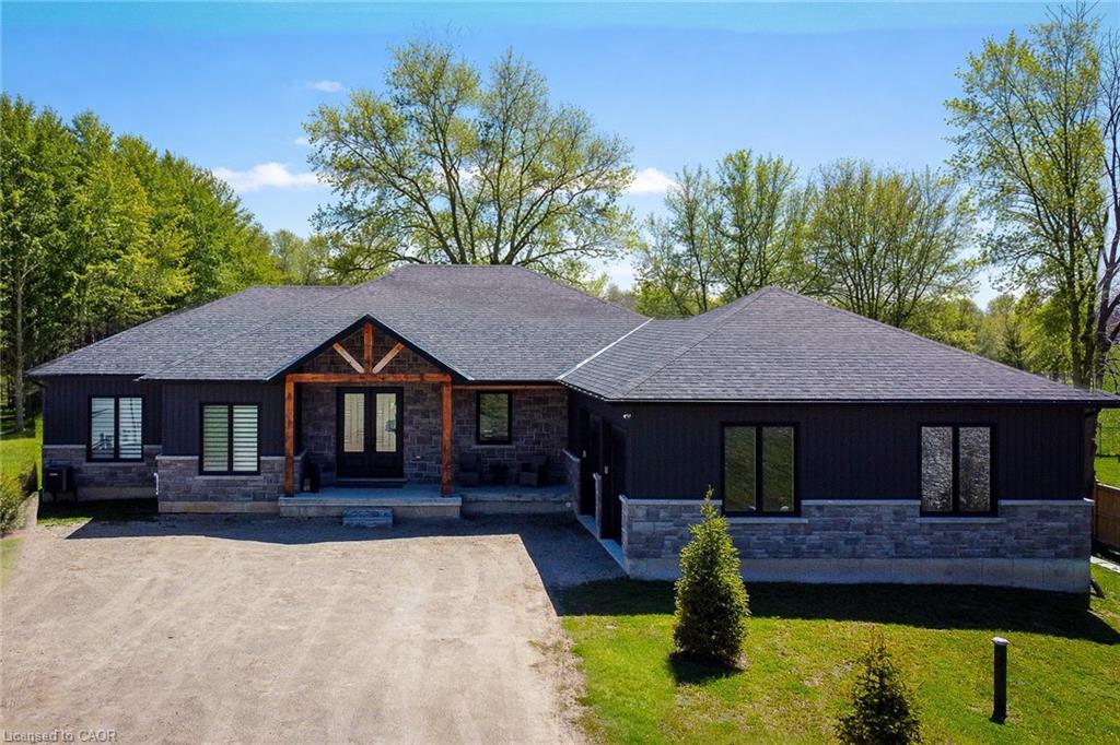 View of front of home with stone siding, covered porch, driveway, and a front lawn