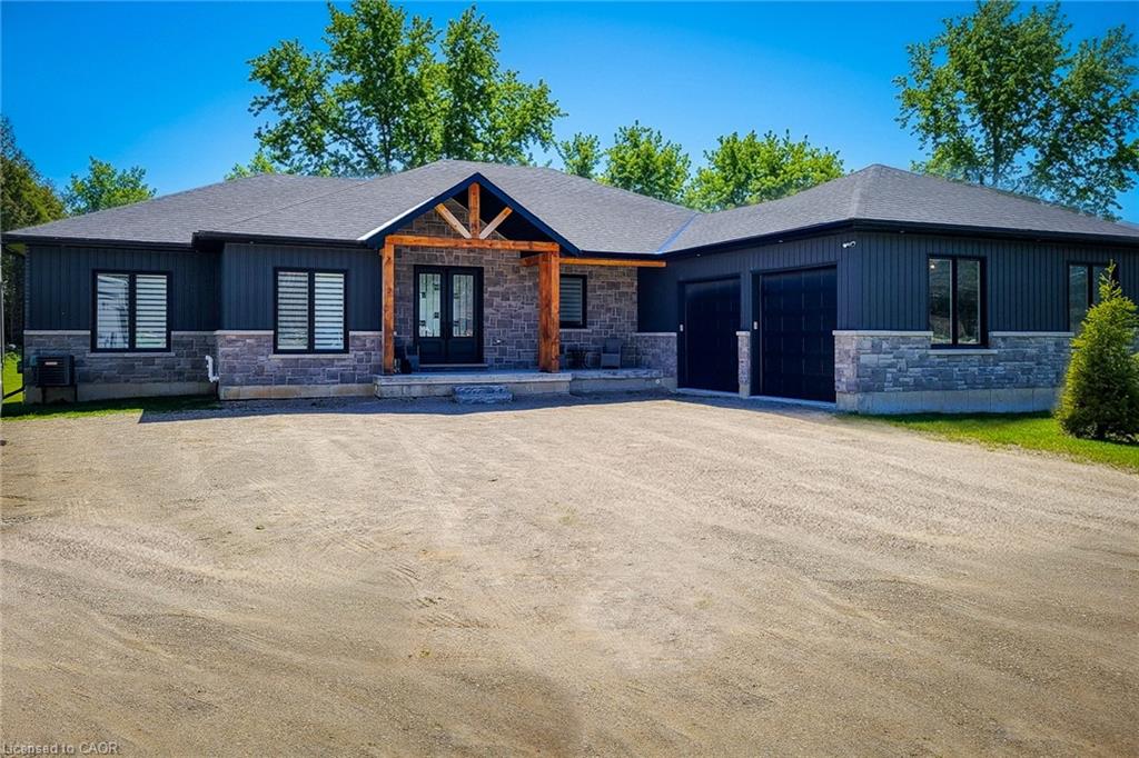 View of front of home featuring stone siding, a garage, dirt driveway, a porch, and french doors