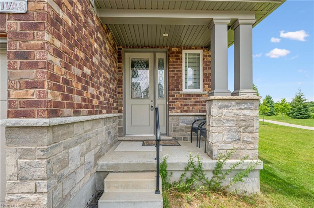 Brick exterior with stone accents, a covered front porch, and a light-colored entry door with decorative glass