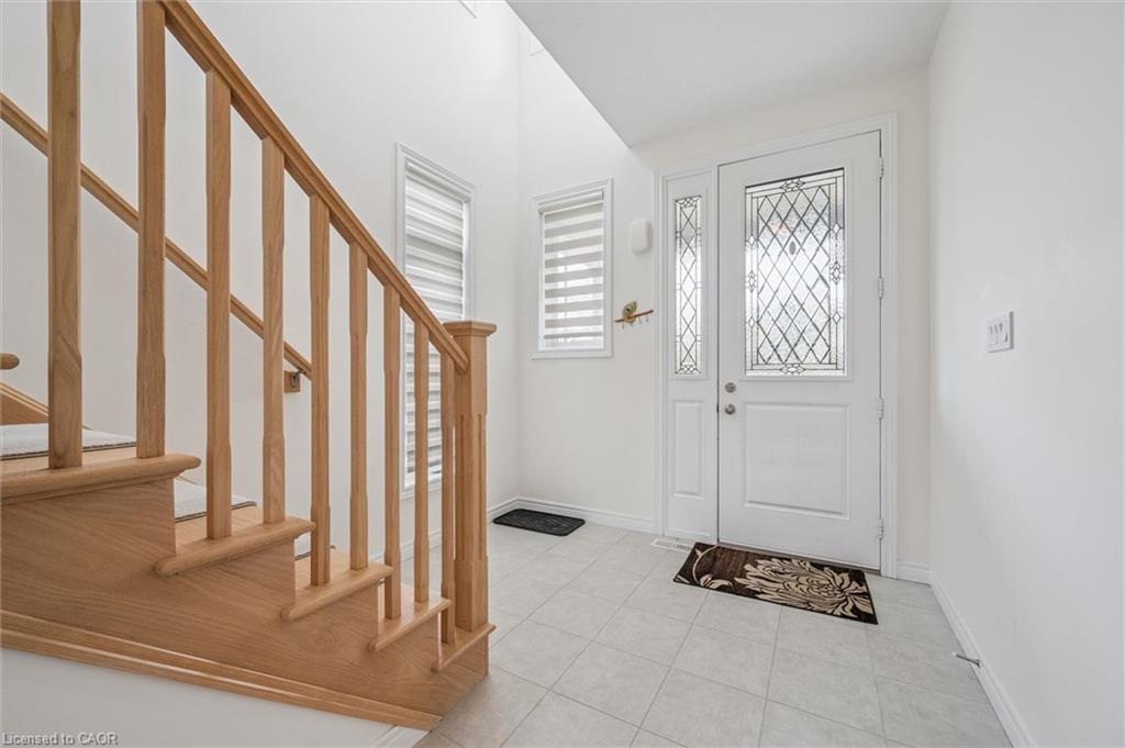 Entryway featuring a decorative glass front door, side panel, and two windows with blinds