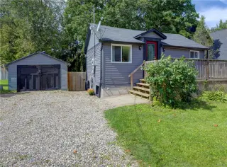 Exterior featuring horizontal siding, a gravel driveway, detached garage, and a wooden deck with railings
