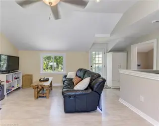Wood-finish flooring throughout, featuring a double window, ceiling fan with integrated lighting, and a glass-paneled exterior door