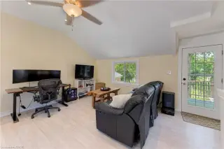 Vaulted ceiling with a ceiling fan, light wood-finish flooring, and a glass-paned door