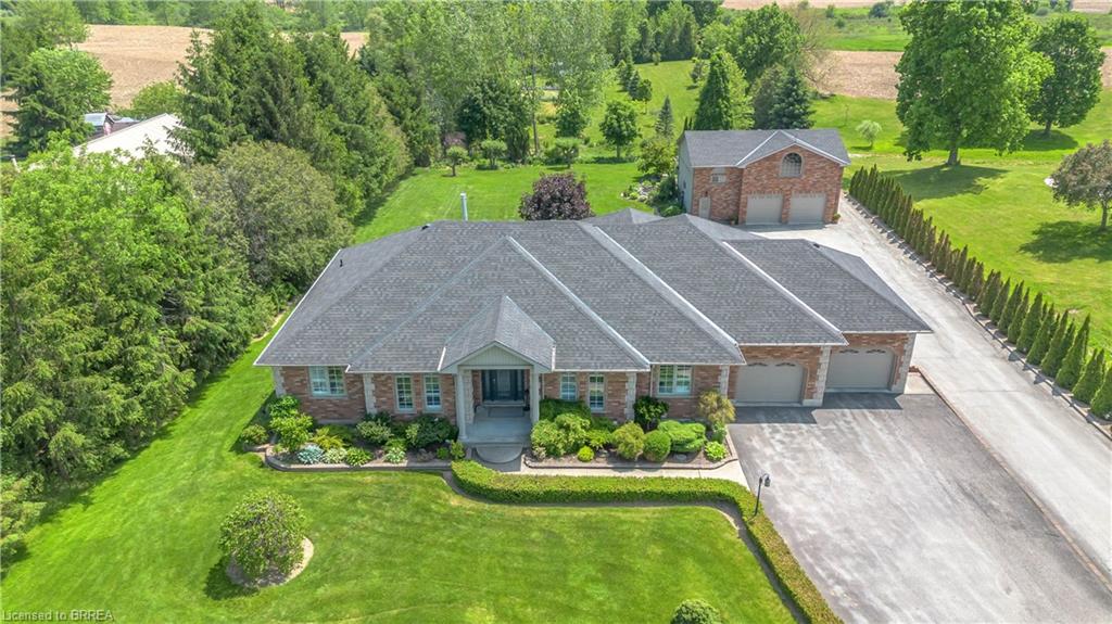 Expansive property featuring a brick exterior, multiple attached garage bays, a paved driveway, and an additional detached garage structure