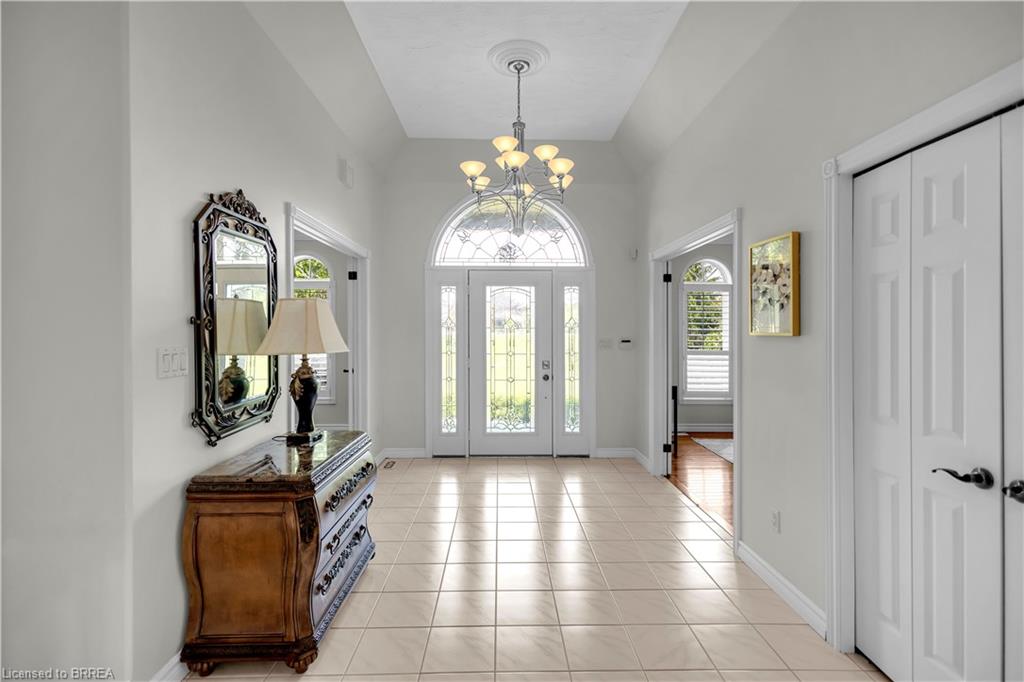 Grand entry foyer featuring tile flooring, vaulted ceiling, and a prominent chandelier
