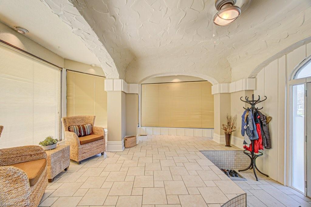 Tiled flooring throughout this versatile interior space featuring arched ceilings, recessed lighting, and expansive windows fitted with blinds