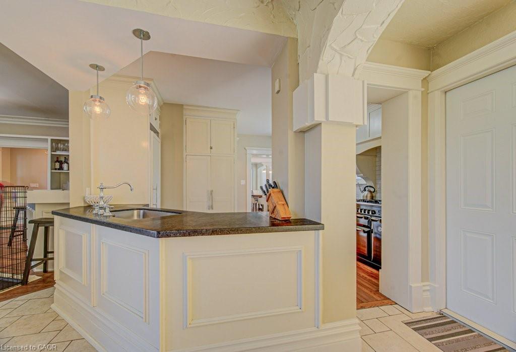 Kitchen island with a dark countertop and undermount sink, illuminated by two clear glass pendant lights