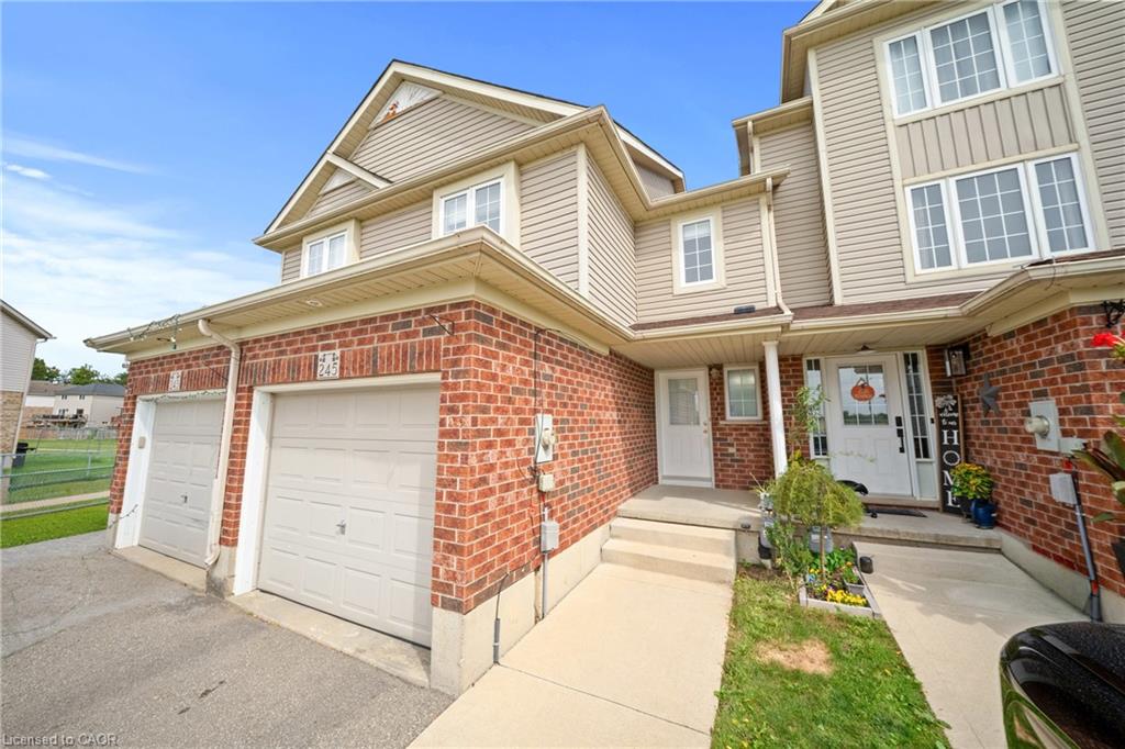 Brick and siding exterior with multiple windows, two garage doors, a concrete walkway, and a covered entry