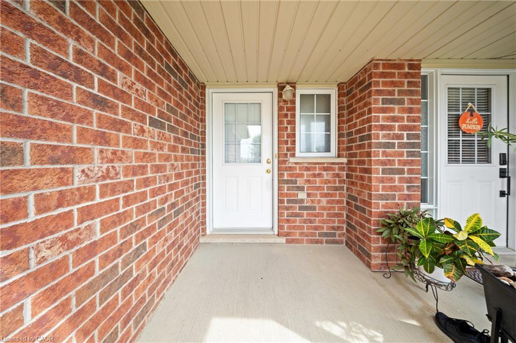 Brick exterior, white entry door with glass insert, white window with grid, covered entryway, and concrete porch