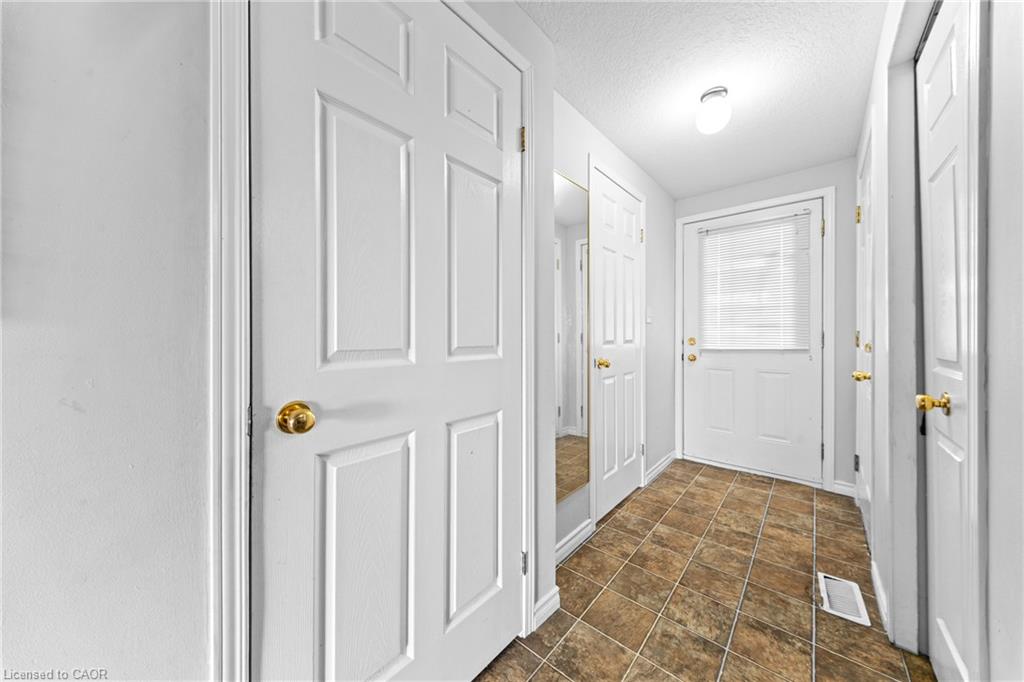 Entryway featuring durable tile flooring, a paneled door with an integrated window, bright overhead lighting, and multiple paneled interior doors with brass hardware