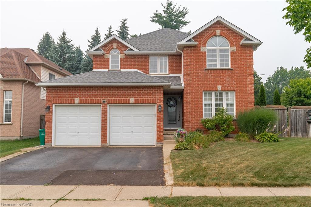 Red brick exterior with a two-car garage, gray front door, and mature landscaping