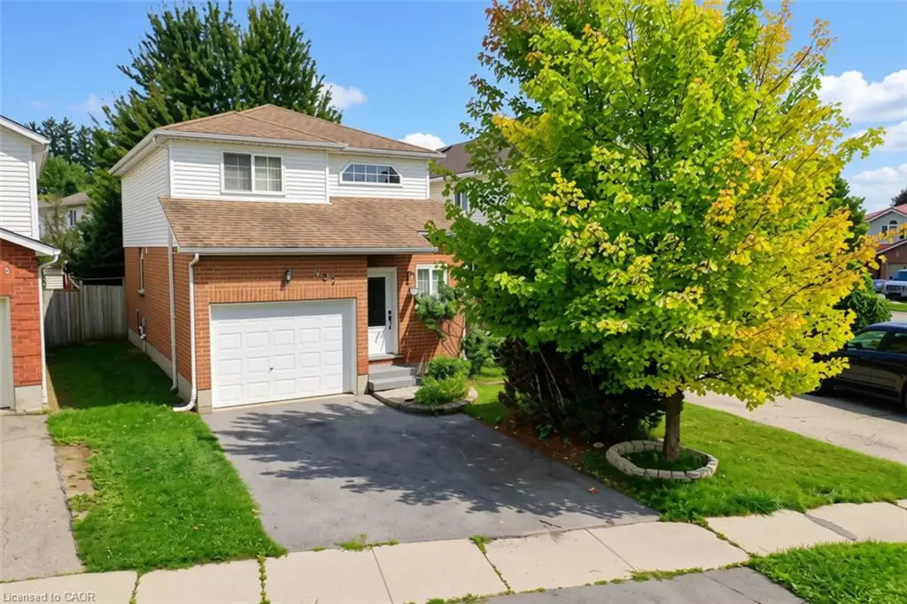 Brick and siding exterior with an attached garage, paved driveway, and mature landscaping