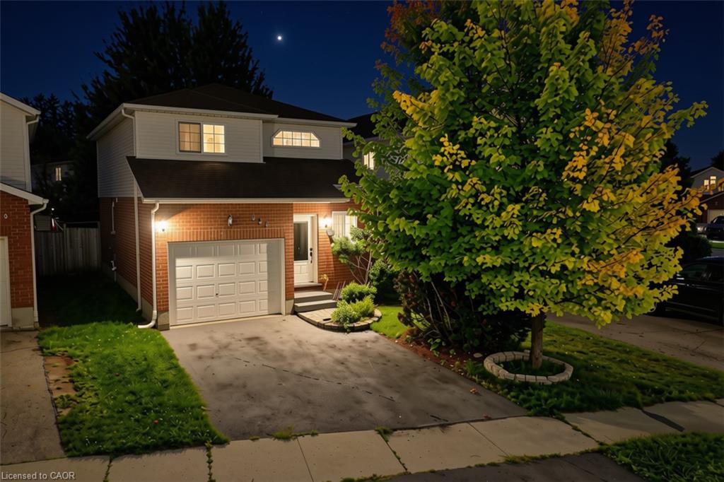 Brick and siding exterior with an integrated garage, paved driveway, and established front landscaping