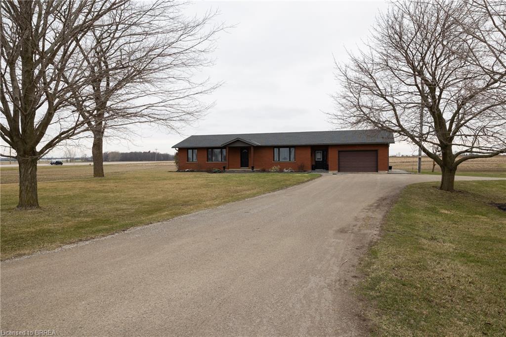 Single story home with a front lawn, driveway, an attached garage, and a rural view