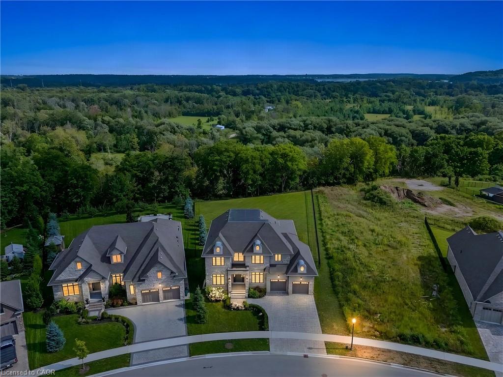 Stone facade residence with a dark shingle roof, arched windows, and a paver driveway