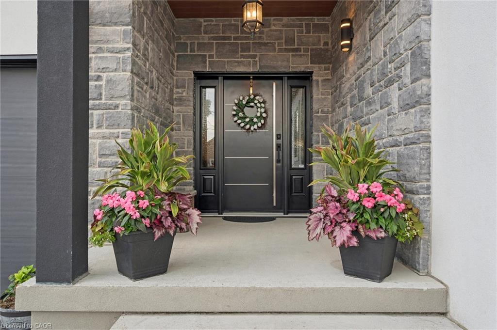 Stone veneer exterior featuring a black entry door with sidelights and covered concrete porch