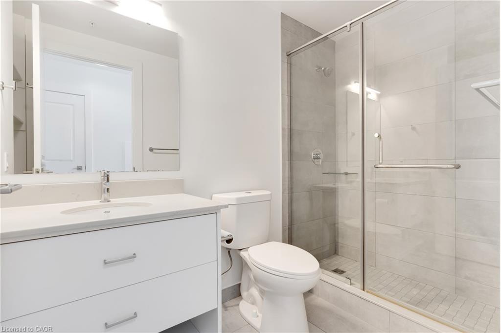 Contemporary bathroom featuring a white vanity with a light-toned countertop, a frameless mirror, and a glass-enclosed shower with subway tile surround