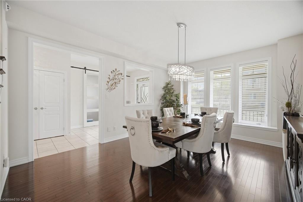 Hardwood flooring extends throughout this space, complemented by a contemporary chandelier and a wall of three windows with blinds