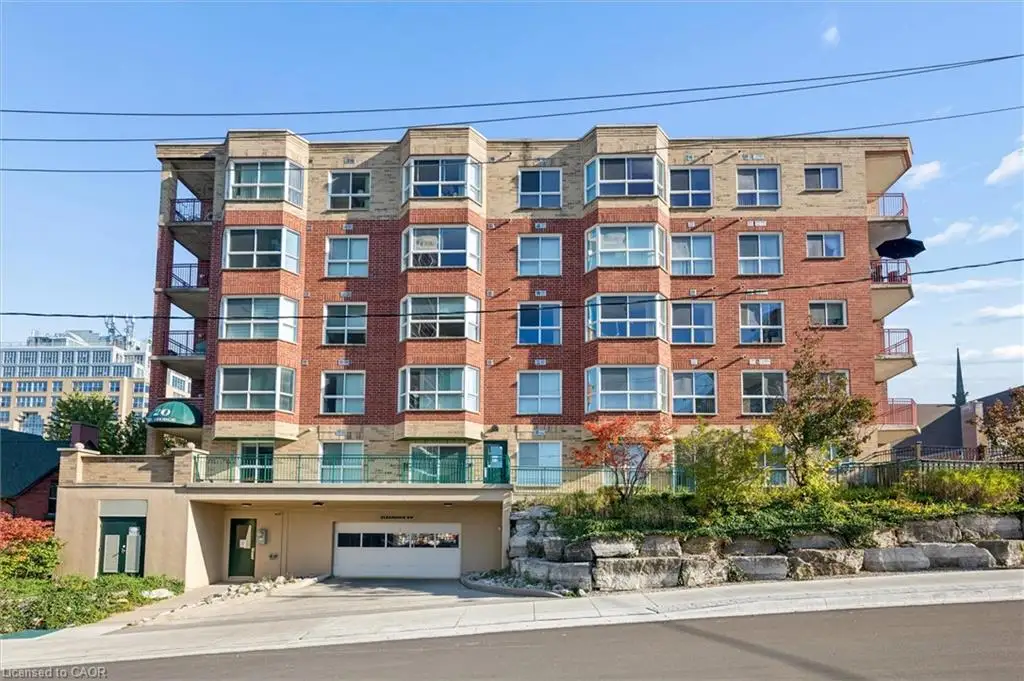 Multi-story building exterior featuring red brick and masonry facade, bay-style windows, private recessed balconies, and integrated garage parking